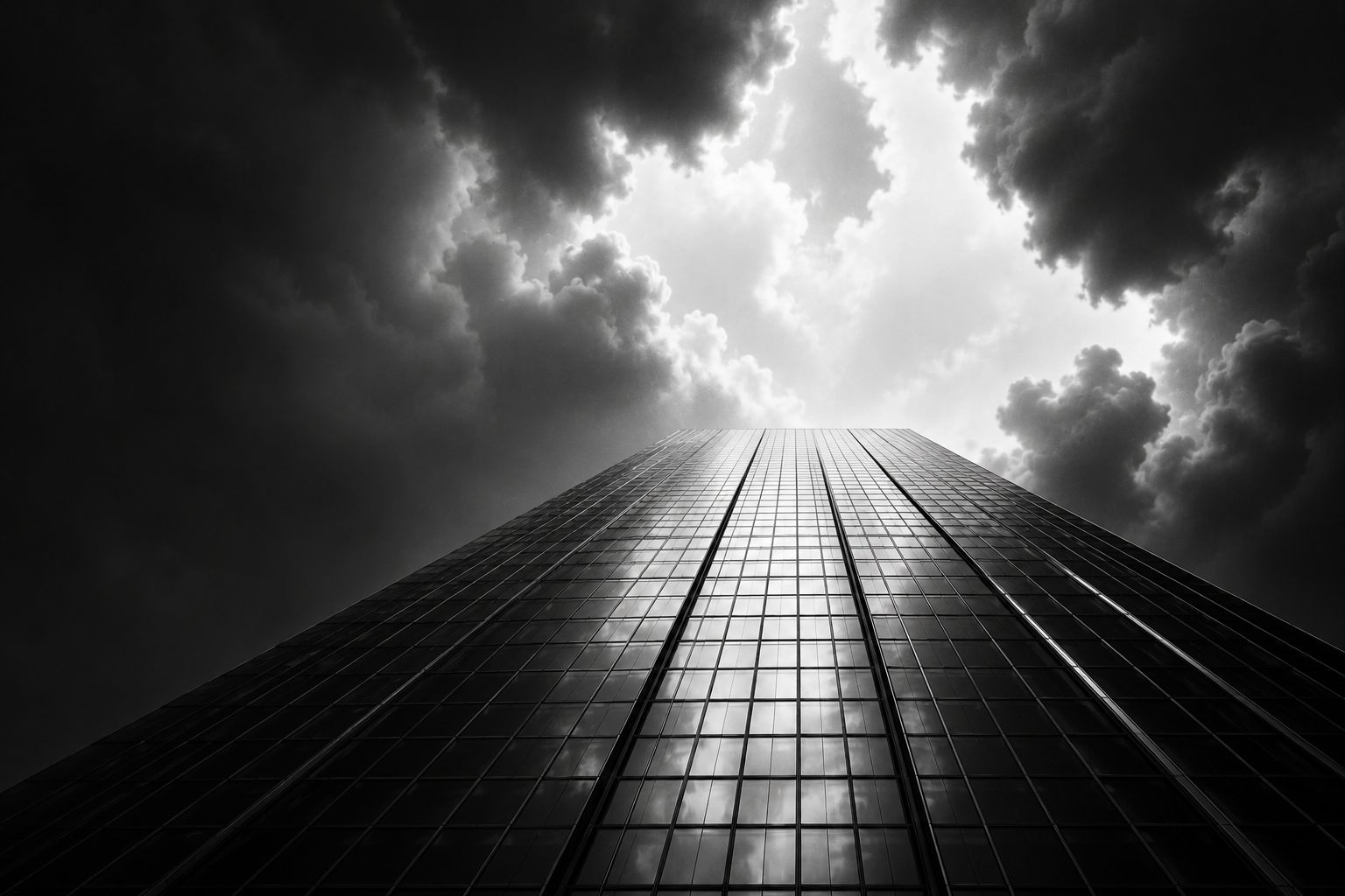 Atmospheric low-angle shot of a glass and steel skyscraper reaching into a dramatic sky.